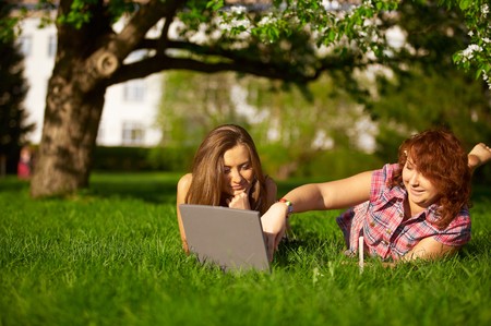 two student girls studying outdoors on grassの写真素材