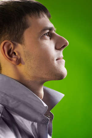 sideview headshot portrait of young handsome brunet guy posing in gray shirt on greenの写真素材