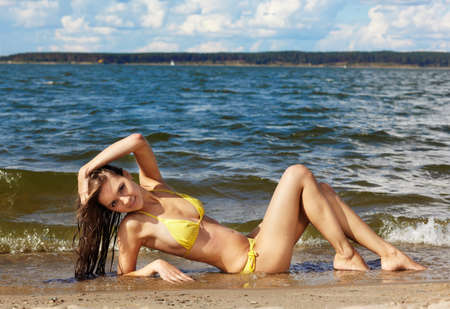Young beautiful slavonic girl in yellow bikini posing on the beachの写真素材