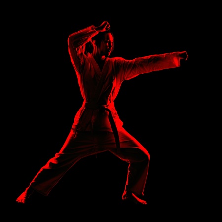 full-length silhouette portrait of beautiful martial arts girl in kimono excercising karate kata on blackの写真素材