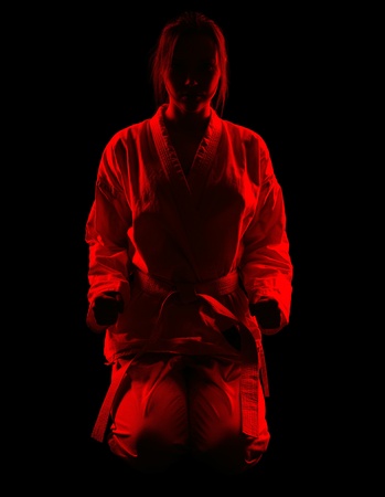 full-length silhouette portrait of beautiful martial arts girl in kimono excercising karate kata on blackの写真素材