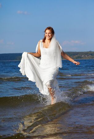 beautiful slavonic bride running in sea wavesの写真素材