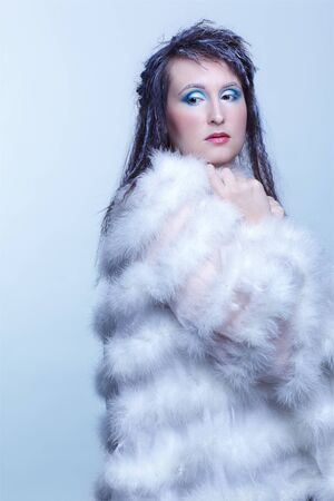 cold tint portrait of beautiful brunette woman in white fur coatの写真素材