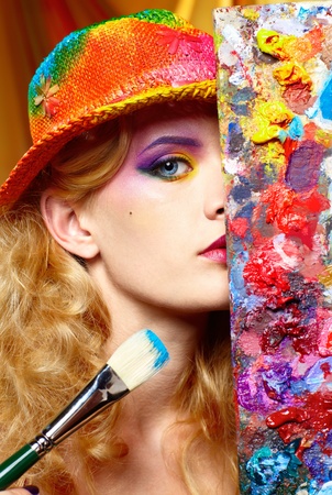 close-up portrait of beautiful woman artist looking from behind of paletteの写真素材
