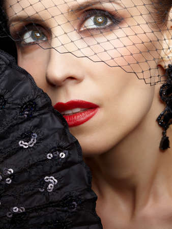 close-up portrait of beautiful brunette woman in veil with fan