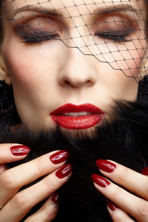 close-up portrait of beautiful brunette woman in veil touching black fur coat with manicured fingers and closing her eyesの写真素材