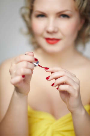 low focus portrait of beautiful young blonde size plus woman model making up red manicureの写真素材