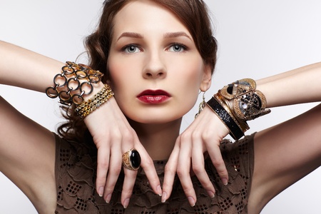 portrait of beautiful young brunette woman in braceletes and ring on grayの写真素材