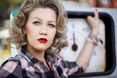 outdoor portrait of young beautiful blonde woman posing with gas pump on backgroundの写真素材