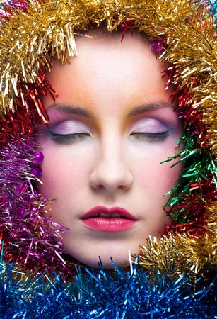 Christmas masquerade portrait of young woman with tinsel and closed eyesの写真素材