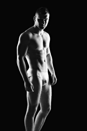 Silhouette of young athlete bodybuilder man on black の写真素材
