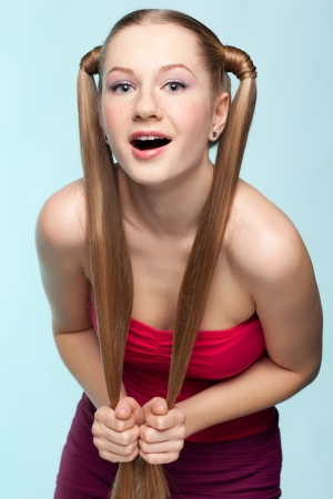 Beautiful playful freckled girl in red dress on blue backgroundの写真素材