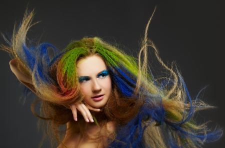 portrait of young beautiful red-haired woman with waving hair colored with green blue and redの写真素材