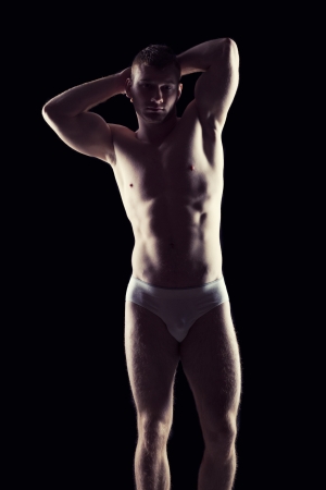 Silhouette of young athlete bodybuilder man on black の写真素材