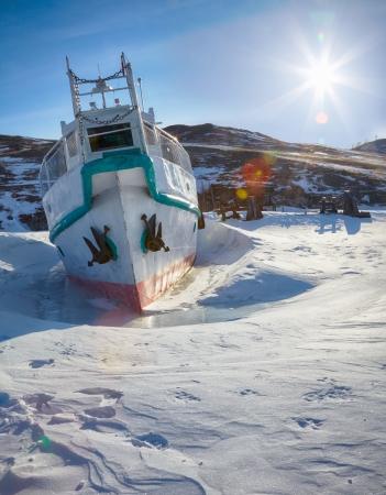 Ship at moorage in frozen baikal lake at winter under Sun raysの写真素材