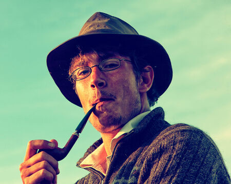 Colorized vintage outdoor portrait of man in hat smoking tobacco-pipeの写真素材