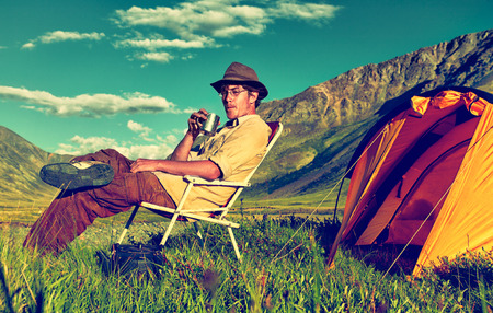 Colorized vintage outdoor portrait of tourist in Altai camp drinking tea near tent and riverの写真素材