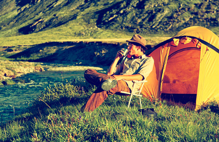 Colorized vintage outdoor portrait of tourist in Altai camp sitting in the chair near the sriverの写真素材
