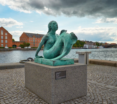 COPENHAGEN, DENMARK - AUGUST 22, 2014:  The bronze copy of Mermaid statue of Anne Marie Carl-Nielsen in front of the main harbour near \"The Black Diamont\" library in Copenhagen, Denmark.のeditorial素材