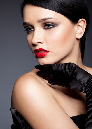 Young brunette woman with long black gloves posing on gray backgroundの写真素材