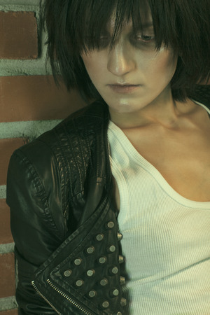 Androgyny female model in Heroin chic style near brick wall. Old style tinted imageの写真素材