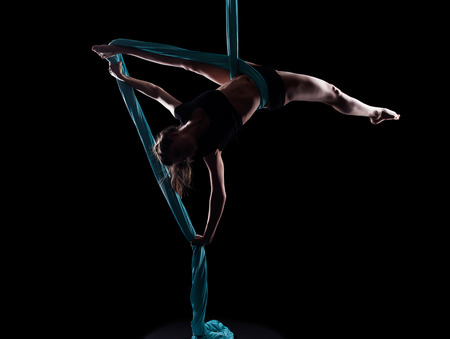 Young woman gymnast with blue gymnastic ribbon isolated on blackの写真素材