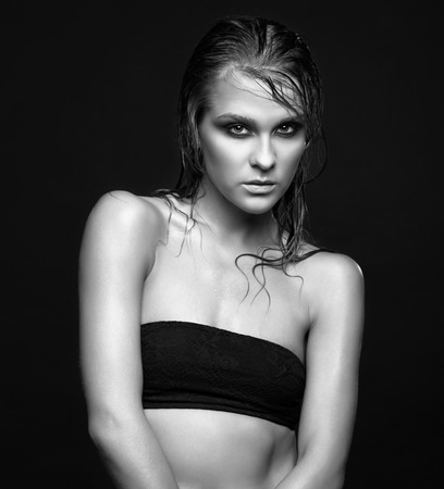 Portrait of young beautiful woman with wet shining  makeup on black backgroundの写真素材