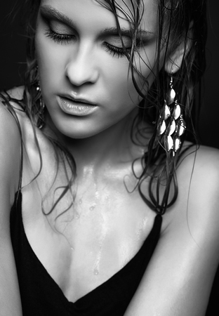 Portrait of young beautiful woman with wet shining  makeup and closed eyes on black backgroundの写真素材