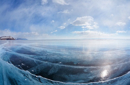 Wide angle shot of winter ice landscape on Siberian lake Baikal with dramatic weather clouds on blue...