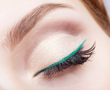 Closeup shot of female face makeup with closed eye and green eyelinerの写真素材