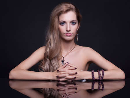 Portrait of young beautiful woman sitting at mirror table on black backgroundの写真素材