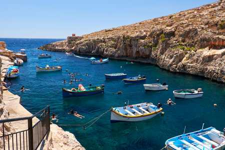 Wied Zurrieq Fjord, MALTA - JULY 24, 2015:  Maltese boats and swimming people in water  near Blue Grotto on south end of Malta islandのeditorial素材