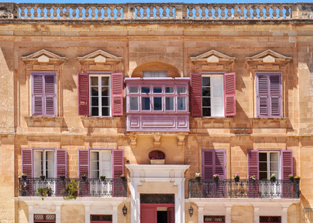 View of one of the residential houses in Mdina with traditional Maltese style open balconies and red shutters, Malta.のeditorial素材
