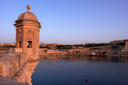 The early morning view of the Senglea Guard tower with sculpted symbols  (crane bird, ear and nose) on the background of Grand harbour. Senglea, Malta.の写真素材