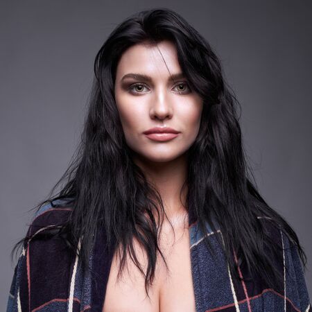 Portrait of a young brunette woman in bathrobe, with long black streaming hair on gray backgroundの写真素材
