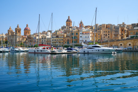 BIRGU, MALTA - JULY 23, 2015: The view of historical buildings across the Dockyard creek  with the yachts and ships moored in the harbour, Birgu, Maltaのeditorial素材