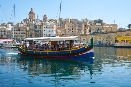 BIRGU, MALTA - JULY 23, 2015: The view of traditional Maltese boat Luzzu, serving as a walking  dinghy in Dockyard bay on the background of Birgu city. Maltaのeditorial素材