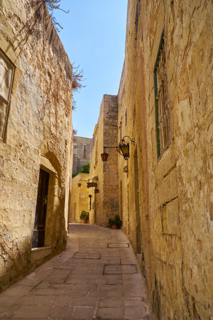 MDINA, MALTA - JULY 29, 2015: In the surroundings of limestone walls. The narrow medieval stone paved street of Mdina, the old capital of Maltaのeditorial素材