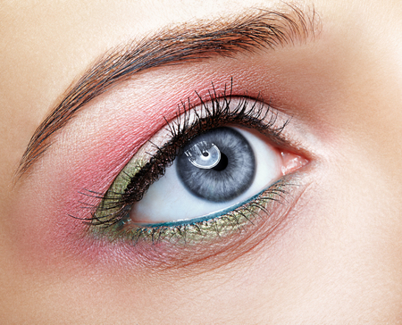 Closeup macro image of human female eye with pink and green makeupの写真素材