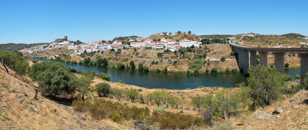 Panoramic view of Mertola with the old mediaeval castle on the hill and the bridge over the Guadiana river as viewed from the high opposite side of the river. Baixo Alentejo. Portugalの写真素材