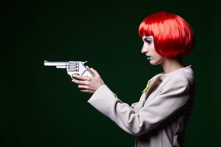 Portrait of young woman in comic pop art make-up style. Female with gun in hand.の写真素材