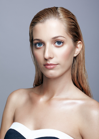 Portrait of beautiful girl. Young woman with long blonde hair. Female in black dress posing on gray background.の写真素材
