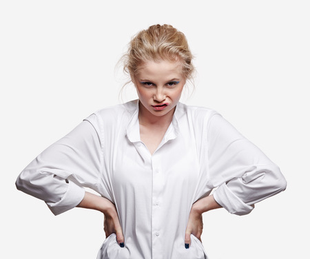 Emotional portrait of a young blonde woman on gray background. Female with grimace on face and hands...