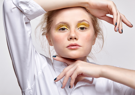 Portrait of a young blonde woman in white blouse on gray background. Female with dreamy lookの写真素材