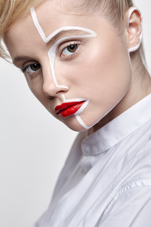 Side view of beautiful young woman on gray background. Female with an unusual creative makeup face paintingの写真素材