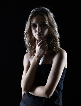Beauty portrait of young woman. Female with wavy hair on black background. Girl with hands near face.の写真素材