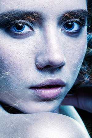 Beautiful young woman with vogue shining sparkle face makeup. Female portrait cinematic blue toned.の写真素材