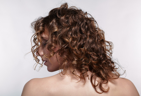 Woman from backside on gray background. Female with curly hair.の写真素材