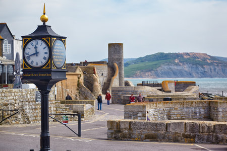 LYME REGIS, ENGLAND - MAY 12, 2009: Lyme Regis 20th century conflicts clock in the Cobb Gate Car Park and the Gun Cliff on the background. Lyme Regis. Englandのeditorial素材