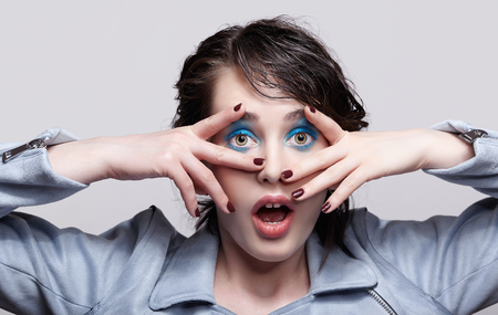 Portrait of female in blue jacket. Woman with unusual beauty makeup and wet hair. Girl with perfect skin, green pistachio colour eyes and blue shadows make-up.の写真素材